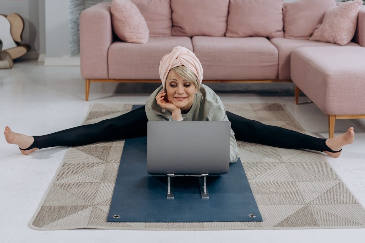 A woman in her living room doing floor exercise in front of her Laptop